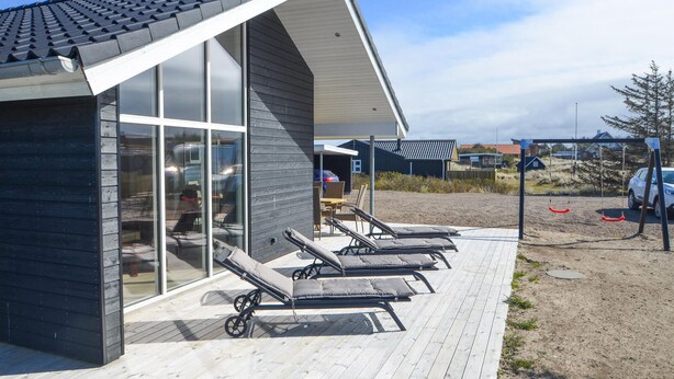 Een modern gebouw met grote ramen en een overdekt buitengebied met lounge stoelen.