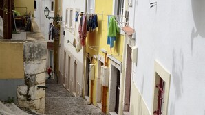 A narrow street with buildings on either side, a laundry line, and a cobblestone path.