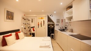A compact hotel room with a bed, a kitchenette, and a small bathroom.