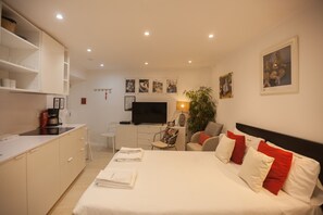 Hotelkamer met een bed, bureau, stoel, televisie en kunst aan de muren.
