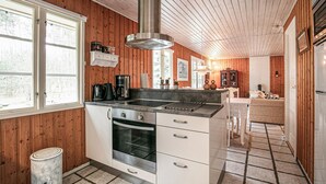 Una cocina con paneles de madera, una campana extractora de acero inoxidable y un horno empotrado.