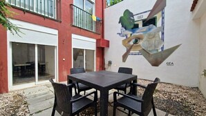 An outdoor patio with a table and chairs, a mural on the wall, and a building with a red facade and a balcony. - FLH Graça Artistic Studio (Lisbon)