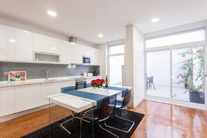 A modern kitchen with white cabinets, a dining table with blue chairs, and a black rug.