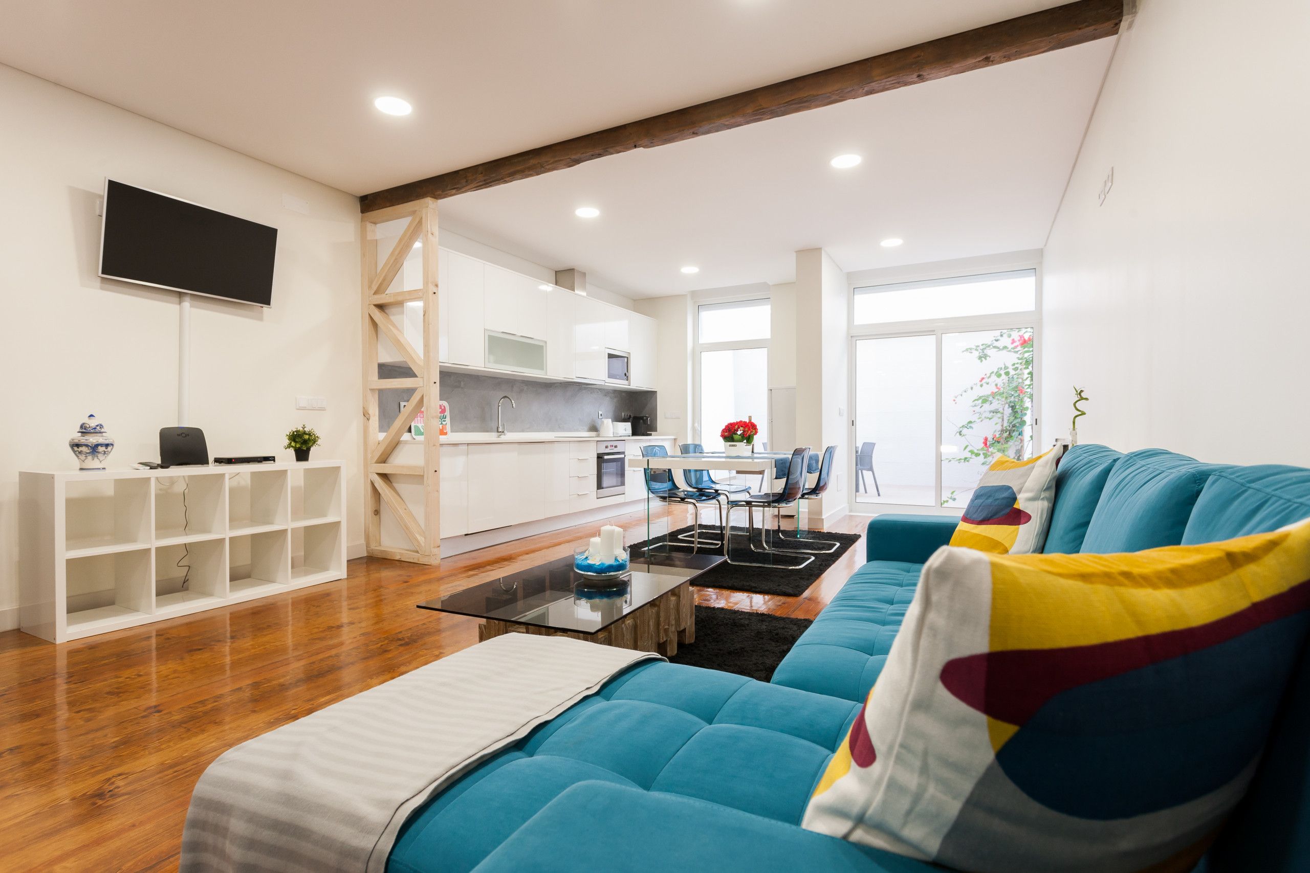A modern living room with a blue sofa, a glass coffee table, and a white entertainment unit.