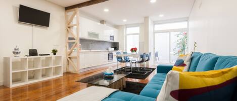 A modern living room with a blue sofa, a glass coffee table, and a white entertainment unit.