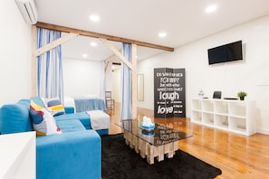 A modern living room with a blue sofa, a glass coffee table, and a motivational quote on the wall.