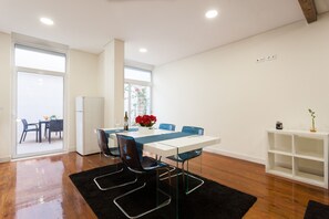 A modern dining area with a white table, blue chairs, and a black rug.