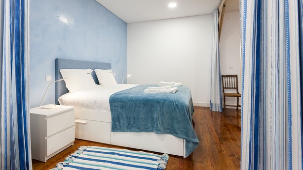 A bedroom with a bed, nightstand, and a wooden chair. - FLH Graça Artistic Studio (Lisbon)