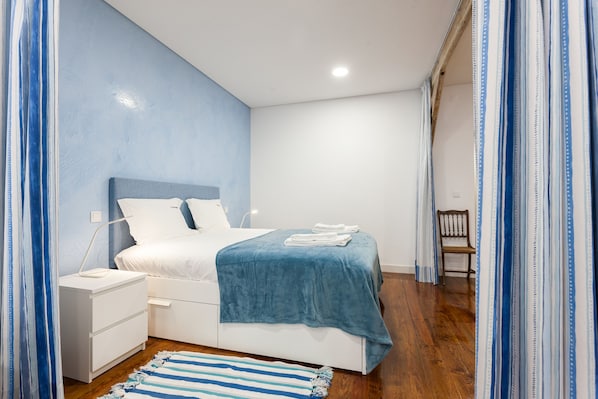 A bedroom with a bed, nightstand, and a wooden chair.