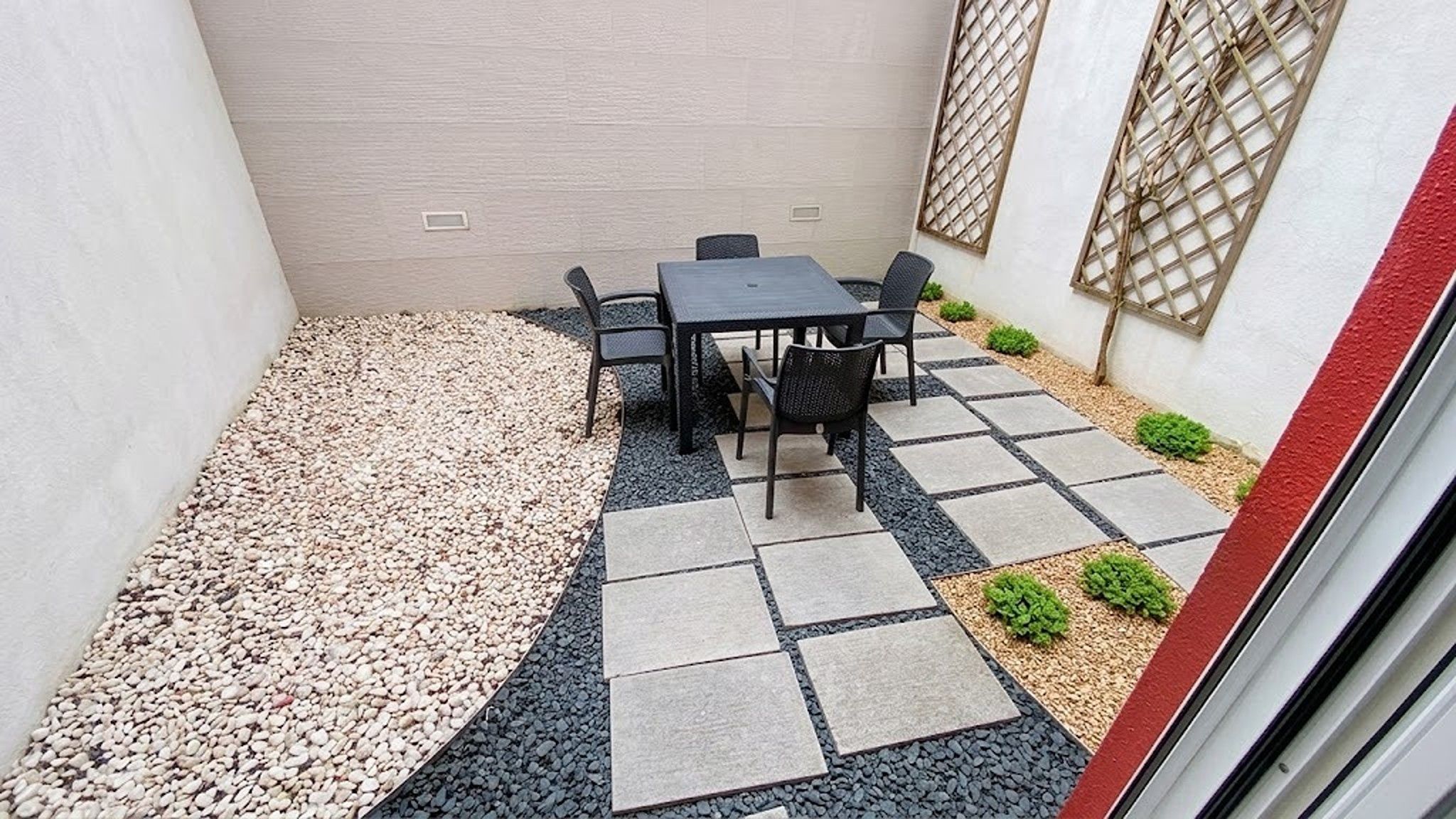 Un patio con una mesa y sillas, rodeado de piedrecitas y adoquines.
