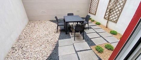 Un patio con una mesa y sillas, rodeado de piedrecitas y adoquines.