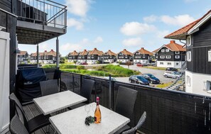 Un balcon avec coin salon extérieur, une vue sur une rangée de maisons traditionnelles et un espace de stationnement.