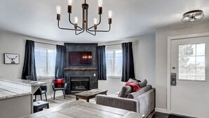 A modern living room with a fireplace, a dining area, and a kitchen counter.