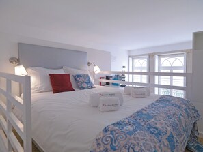 Une chambre d’hôtel avec un lit, des oreillers, une table de chevet, une lampe et une fenêtre.