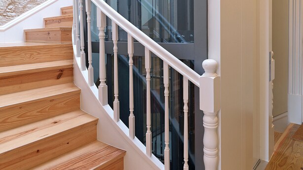 A wooden staircase with white balusters leading to a glass elevator. - FLH Porto Cozy Studio (Oporto)