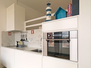 A compact kitchen with a built-in oven and a window overlooking a cityscape.