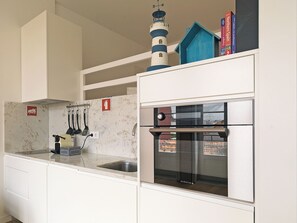 A compact kitchen with a built-in oven and a window overlooking a cityscape.