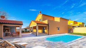 Una proprietà residenziale con piscina, area salotto esterna e barbecue.