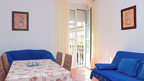 Ein Zimmer mit einem Esstisch, zwei blauen Sofas und zwei gerahmten Bildern an den Wänden.