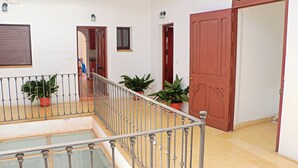 Ein großzügiger Innenbereich mit Balkon, Blumentöpfen und einer großen Holztür.