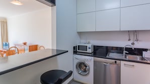 Cocina compacta con lavadora, microondas y fregadero.