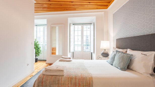 Une chambre spacieuse avec un grand lit, un plafond en bois et une vue par la fenêtre.