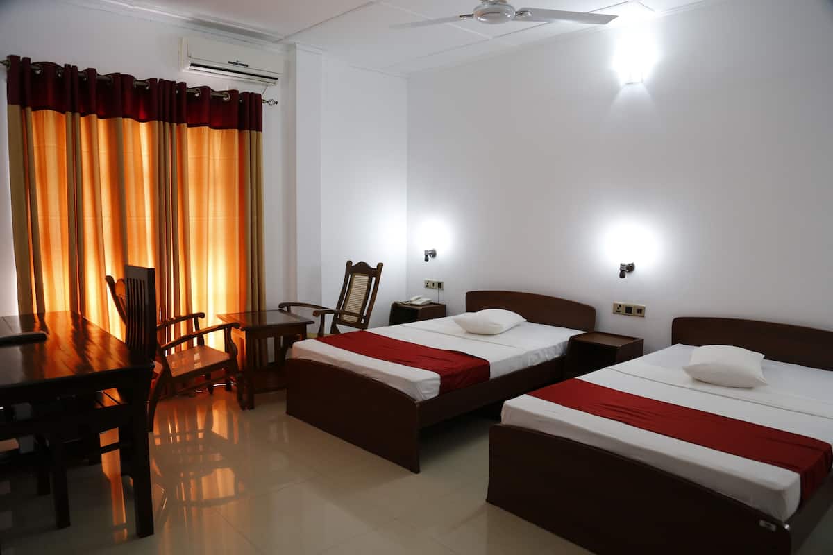 A hotel room with two single beds, a wooden desk, a chair, and a dining table.