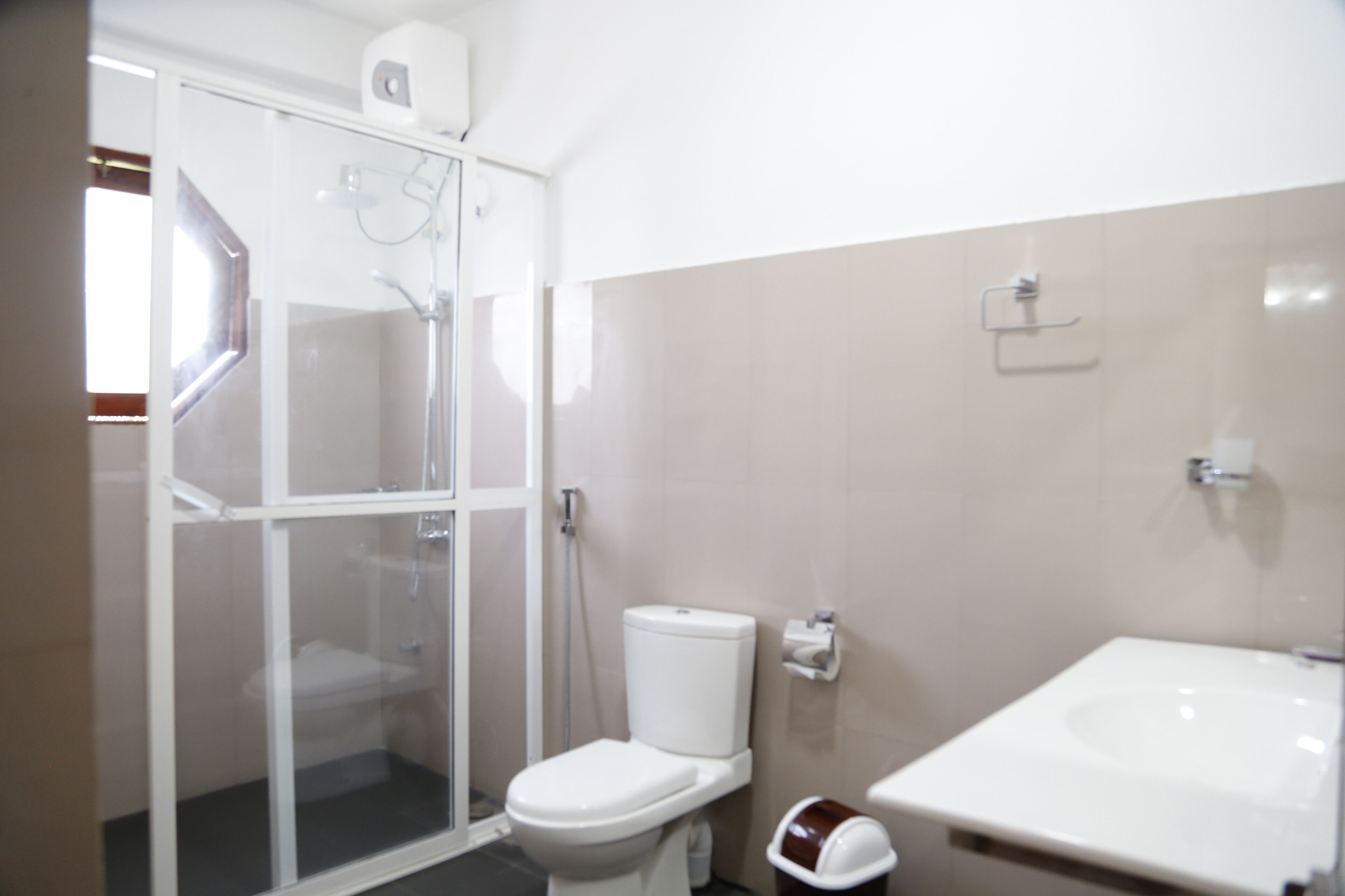 A bathroom with a glass-enclosed shower, a toilet, and a sink.