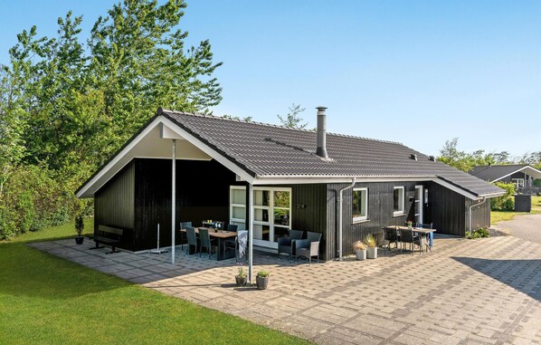 A modern house with a covered patio area, a chimney, and a well-maintained lawn. - Cozy home in Tarm with kitchen (Tarm)