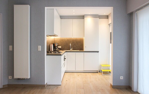 A modern kitchen with white cabinets, a gas stove, and a coffee maker. - Nice apartment in Oostende with WiFi (Oostende)