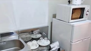 A compact kitchenette with a microwave, kettle, and a small sink. - Sun Hotel (Tokyo)
