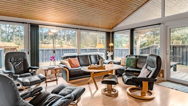 A spacious sunroom with leather furniture, large windows, and a wooden ceiling. - 4 bedroom beautiful home in Saltum (Saltum)