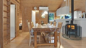 A wooden interior with a dining table, chairs, a clock, and a wood stove. - 4 bedroom beautiful home in Saltum (Saltum)