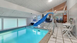 An indoor swimming pool with a blue slide, a clock, and a sign indicating a maximum height of 50 inches. - 4 bedroom beautiful home in Saltum (Saltum)