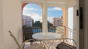 Un balcón con una mesa redonda y sillas, con vista a una piscina y edificios.