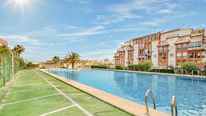 Una piscina con cubierta verde, rodeada de edificios de varios pisos con balcones.