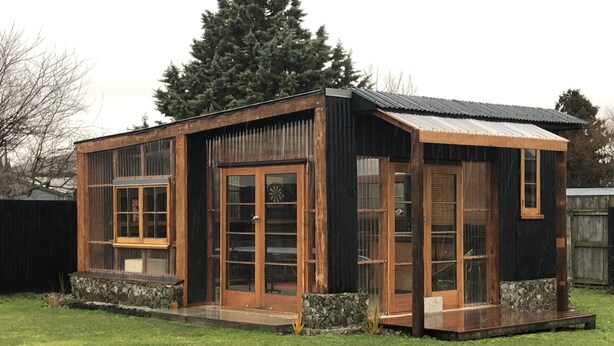 Un pequeño edificio de madera de una sola planta con ventanas amplias y cimientos de piedra.