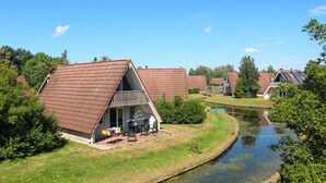 Een rij A-huizen met een klein vijvertje op de voorgrond.