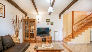 A living room with a sofa, TV, wooden cabinet, and staircase. - 3 bedroom amazing home in Stanjel (Stanjel)
