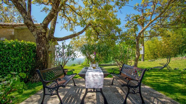 An outdoor seating area with two benches, a table, and a bottle of wine. - 3 bedroom amazing home in Stanjel (Stanjel)