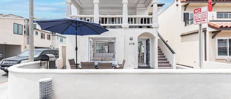 A two-story building with a covered outdoor seating area, a staircase, and a 'No Parking' sign.