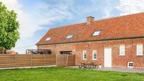A brick building with a tiled roof, a wooden fence, and a grassy yard. - Awesome home in Stavele with WiFi (Stavele)