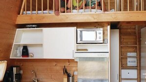 Une cuisine compacte équipée d’une cuisinière, d’un four à micro-ondes et d’un évier, d’un petit réfrigérateur et d’un coin repas avec une table et des chaises.