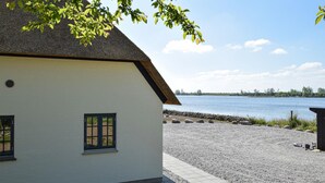 En byggnad med ett halmtak och utsikt över en stilla sjö.