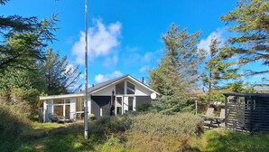 Een modern huis met een groot raam, schoorsteen en een hoge antenne.