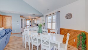 Une cuisine moderne avec des meubles blancs, une table à manger avec des chaises blanches et un banc en bois.