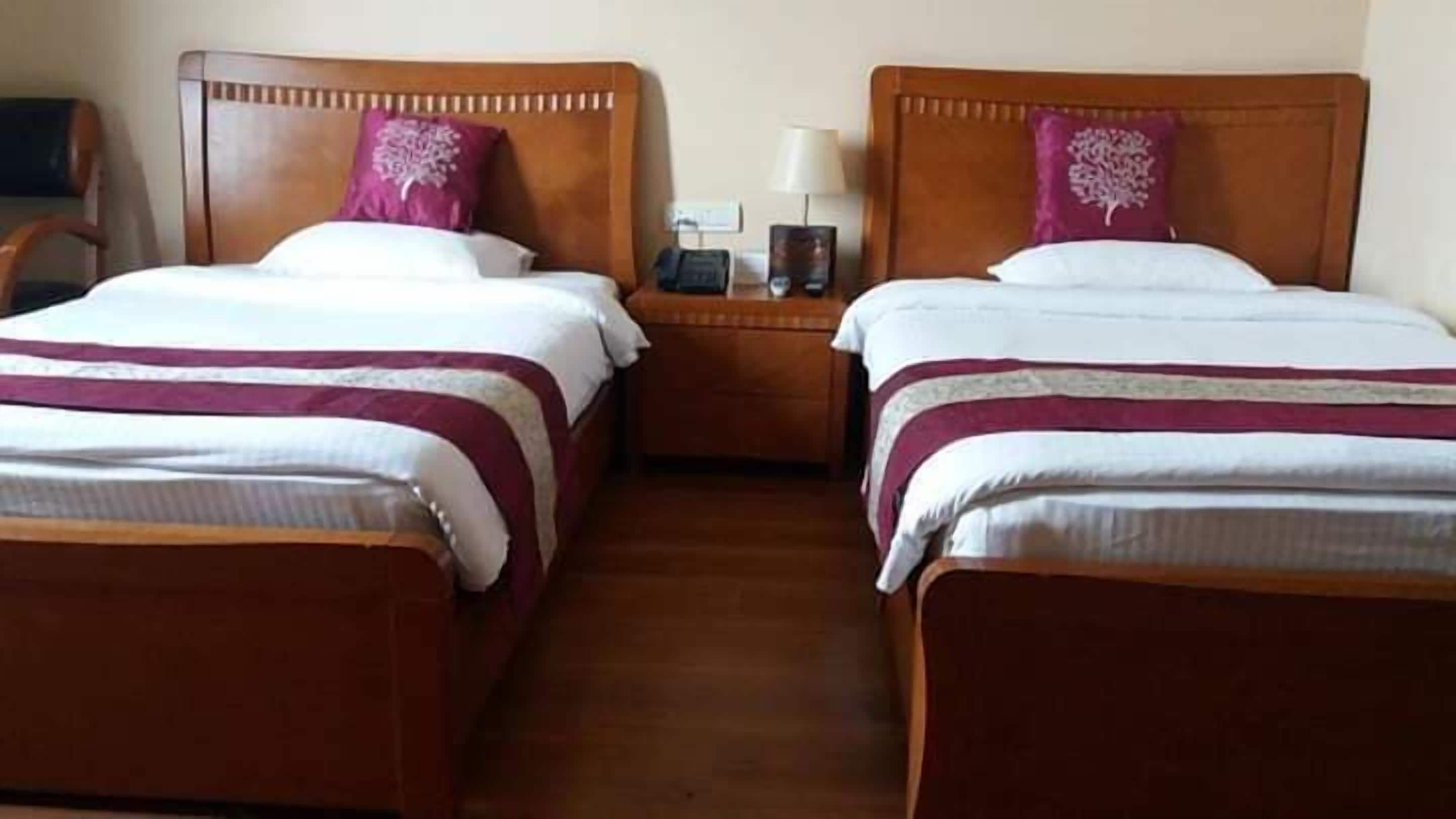 Two adjacent beds with wooden headboards, white bedding, and purple pillows.