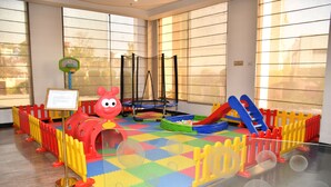 Zona de juegos con un túnel rojo, un trampolín y un tobogán.
