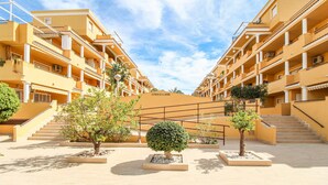 Een meerhoog hotel met een centrale binnenplaats, met een symmetrisch ontwerp, balkons en een heldere lucht.
