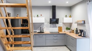 A modern kitchen with grey cabinets, a black microwave, and a wooden ladder. - Awesome home in Nowe Warpno with house sea view (Nowe Warpno)
